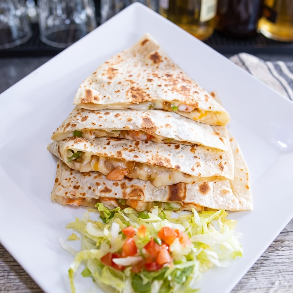 A stack of cheesy quesadillas with shrimp and vegetables, served with a side salad.