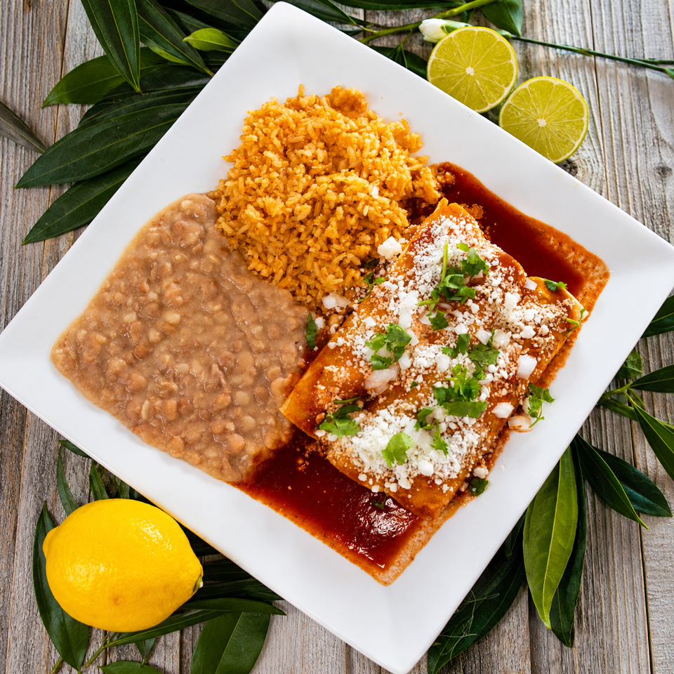 Two enchiladas with red sauce, rice, and refried beans, garnished with cilantro, onions, and cheese.